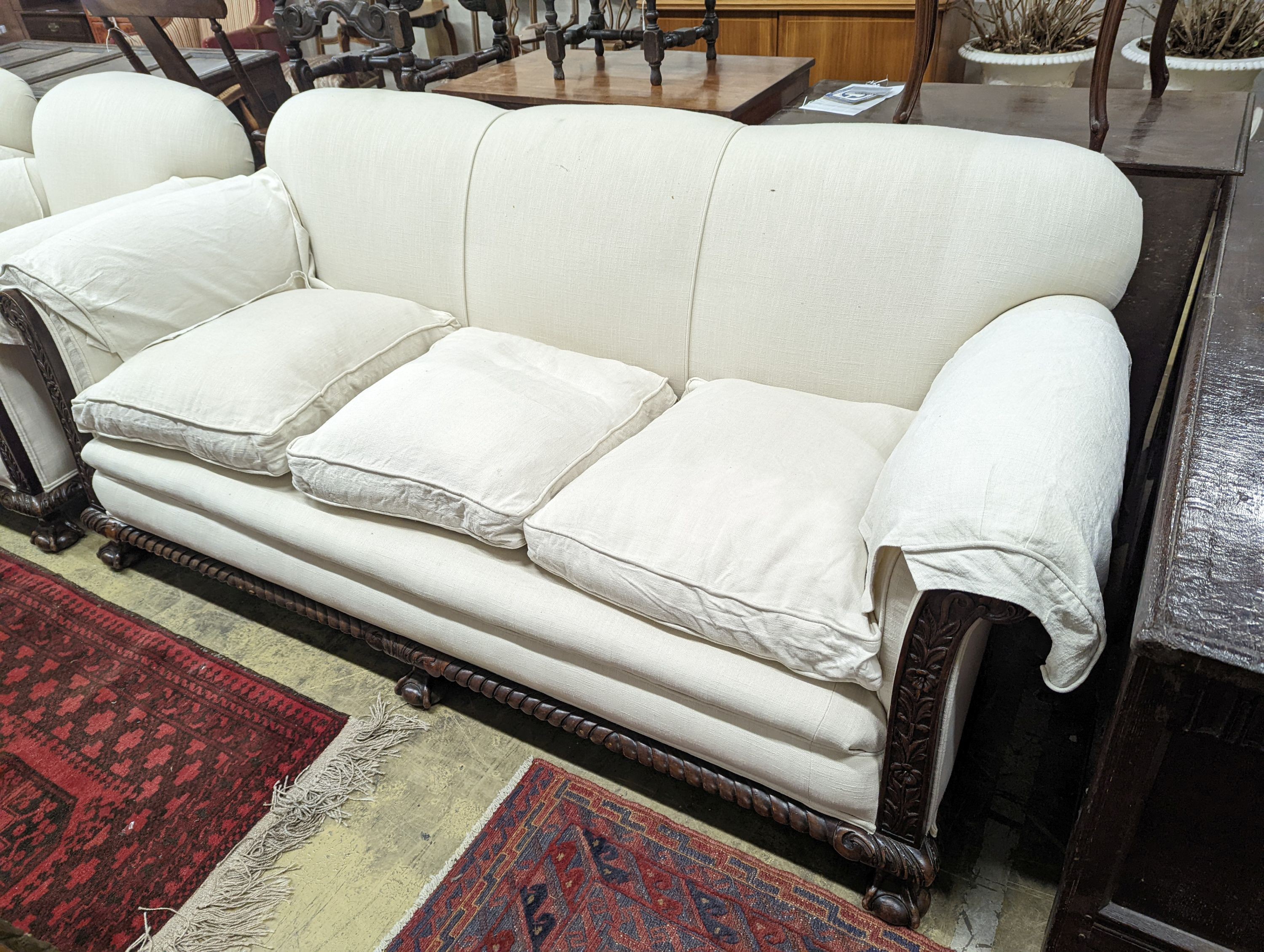 An early 20th century carved mahogany upholstered three piece lounge suite on claw and ball feet, the settee length 194cm, depth 80cm, height 80cm